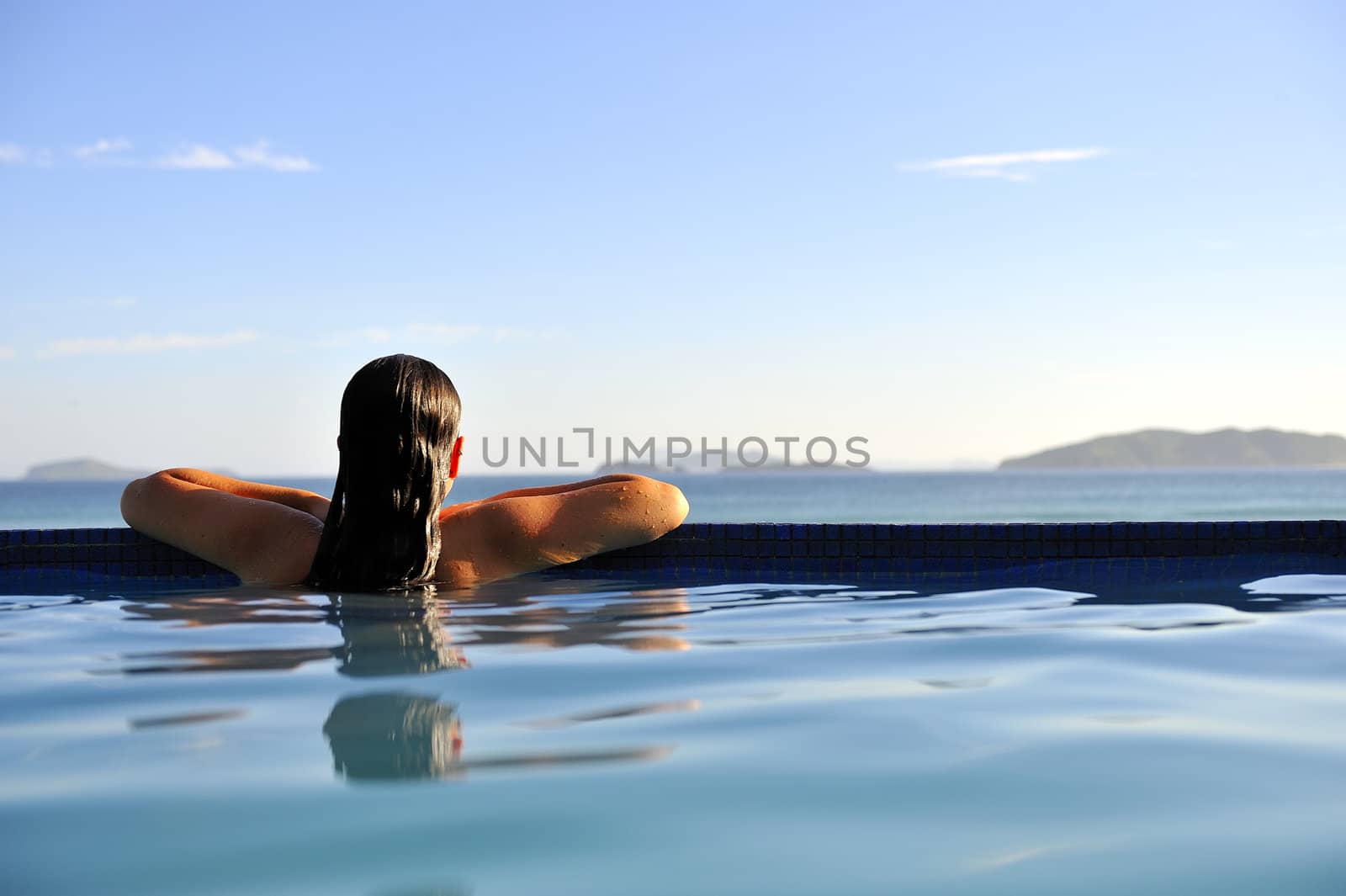 Woman relaxing on a swimming pool with a sea view
