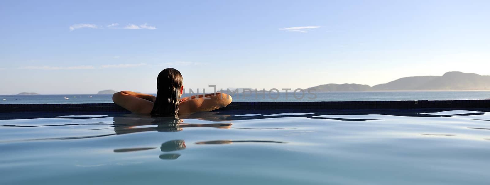 Woman relaxing on a swimming pool with a sea view
