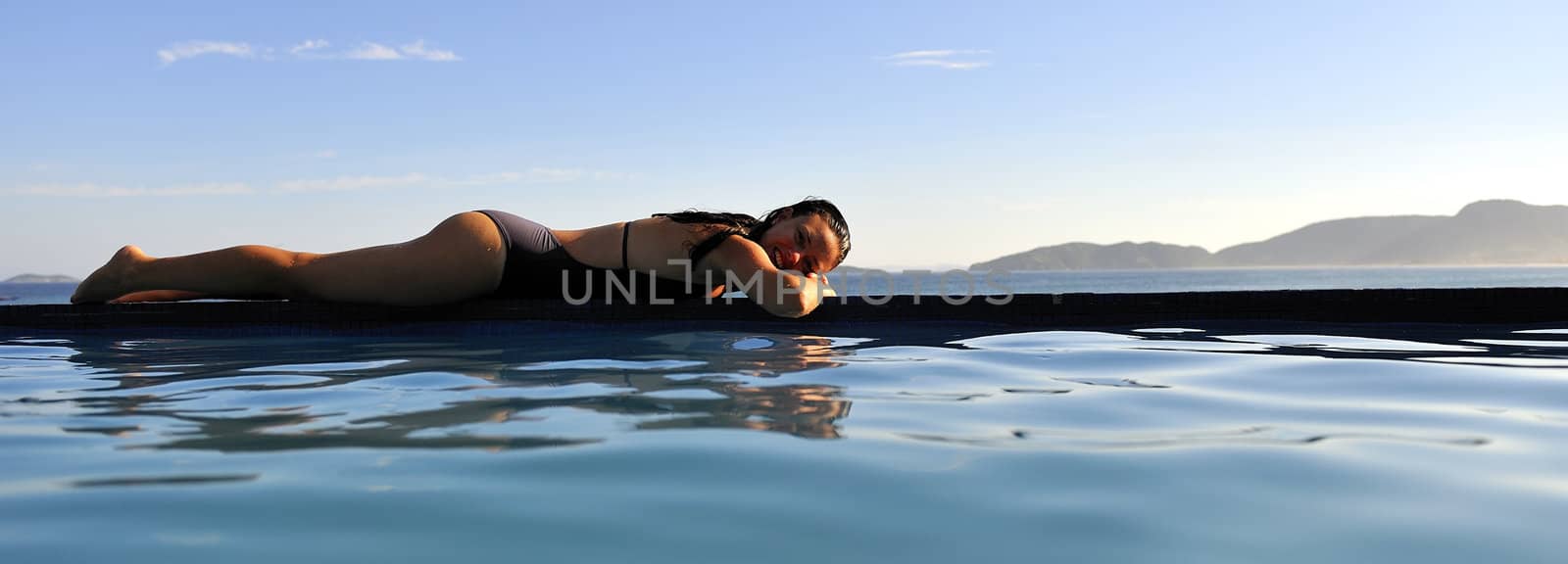 Woman relaxing on a swimming pool with a sea view
