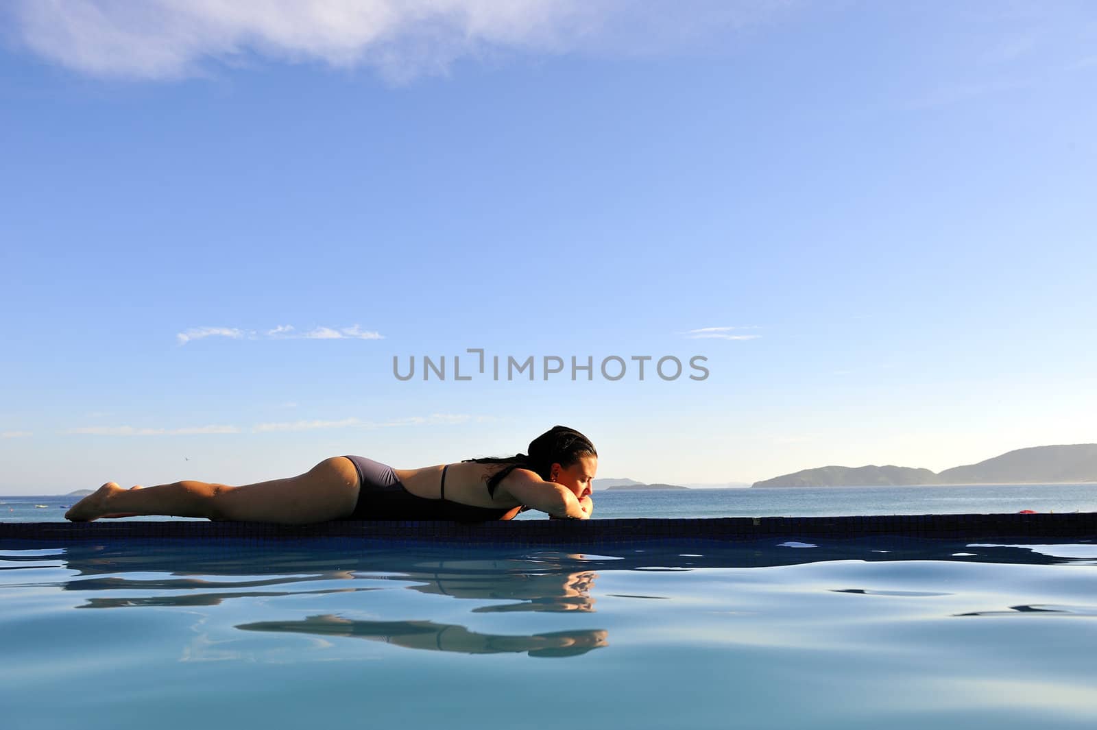 Woman relaxing on a swimming pool with a sea view
