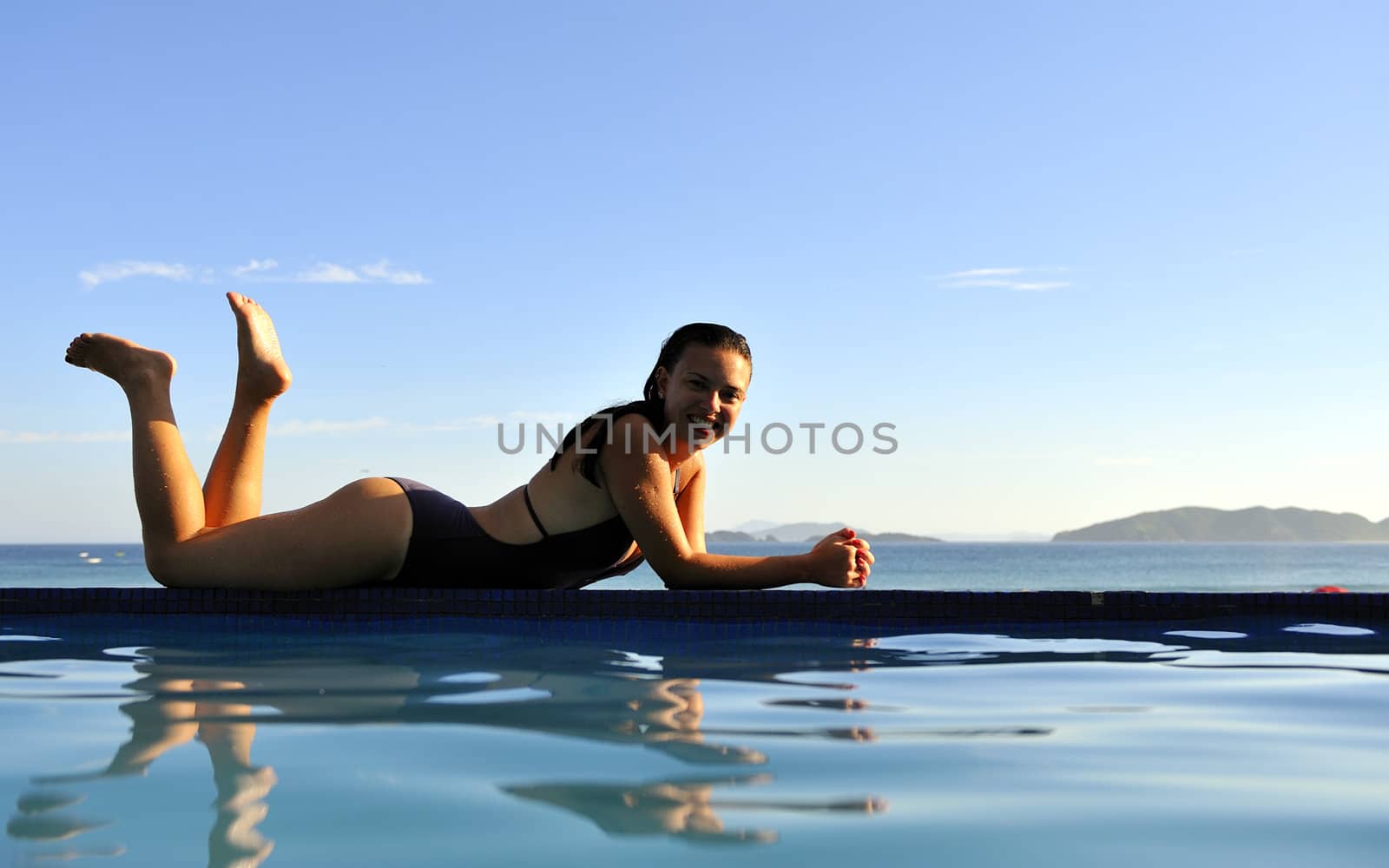 Woman relaxing on a swimming pool with a sea view
