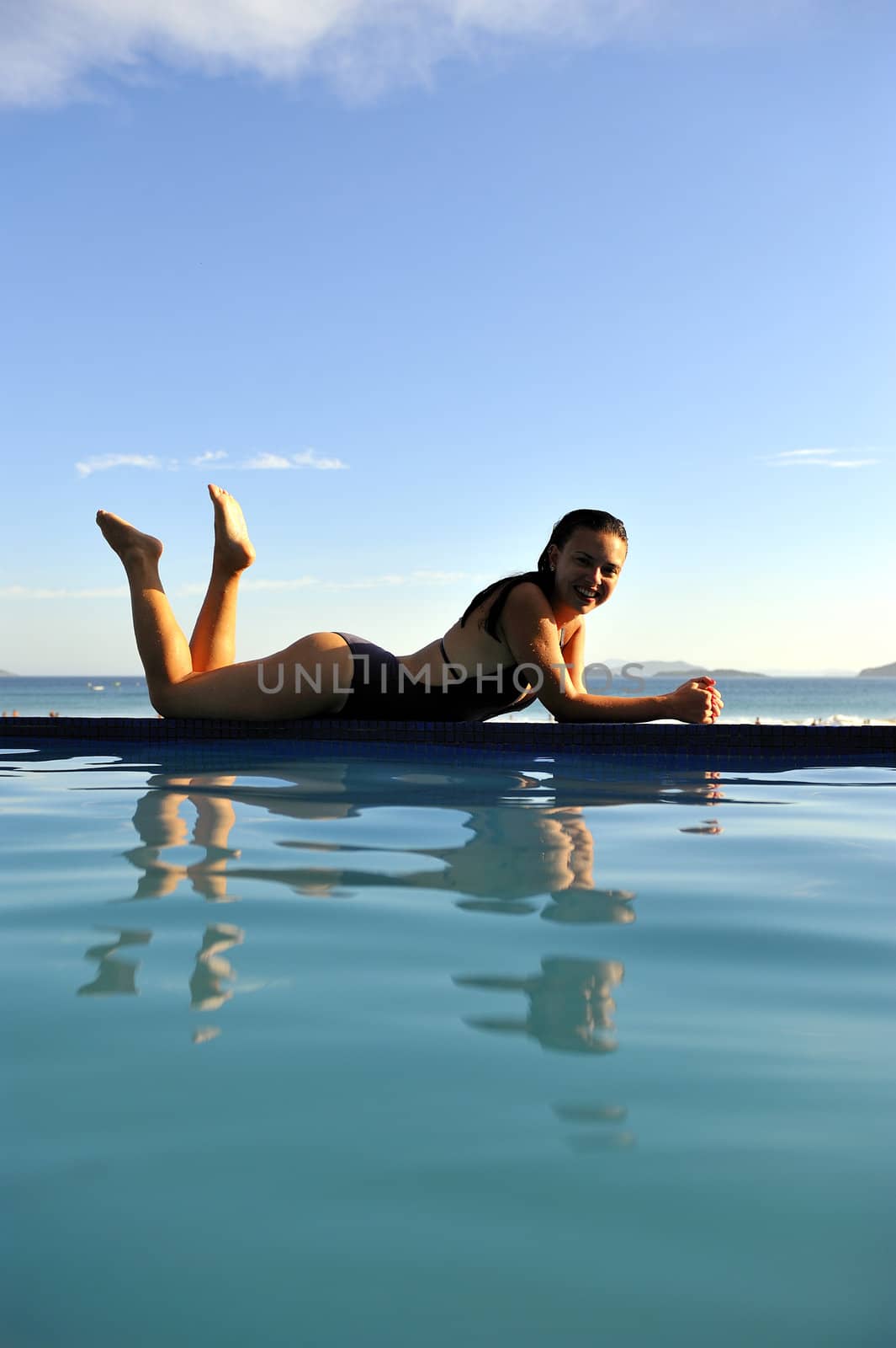 Woman relaxing on a swimming pool with a sea view 
