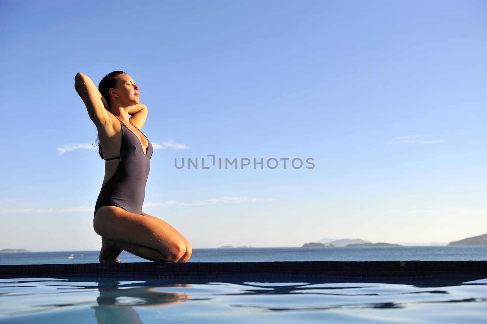 Woman relaxing on a swimming pool with a sea view 
