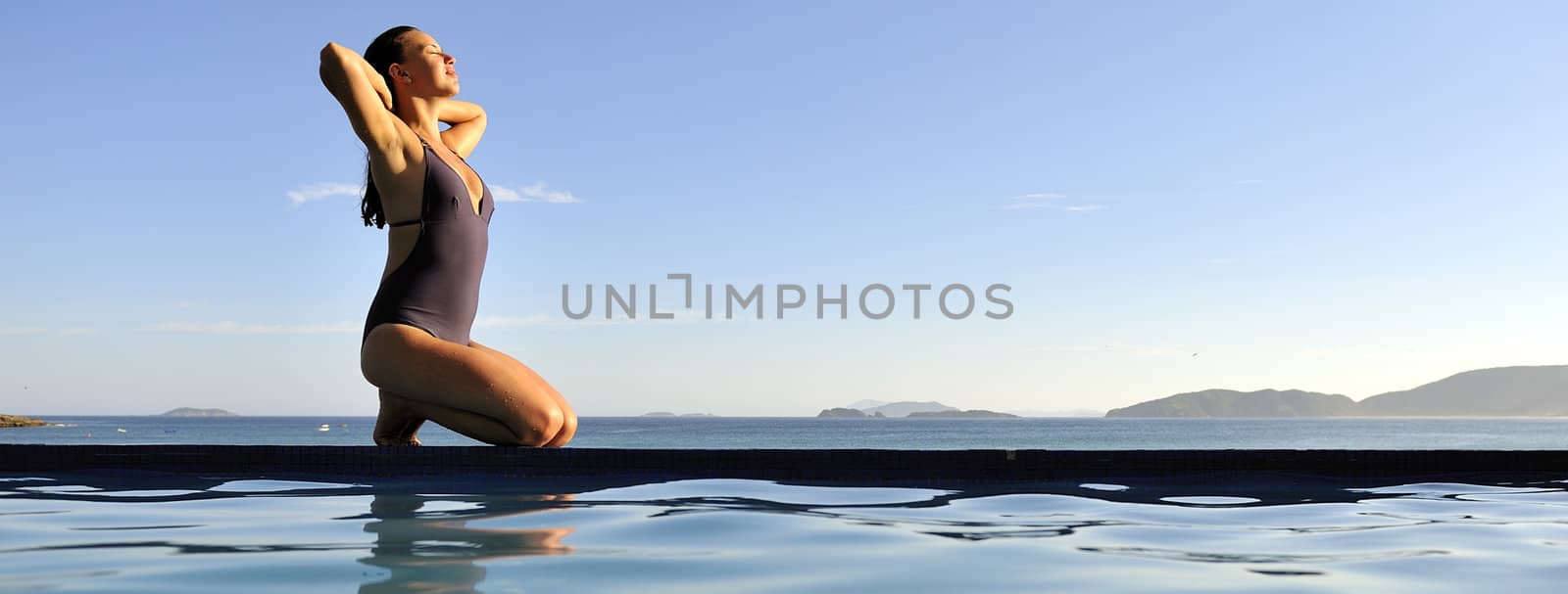 Woman relaxing on a swimming pool with a sea view 
