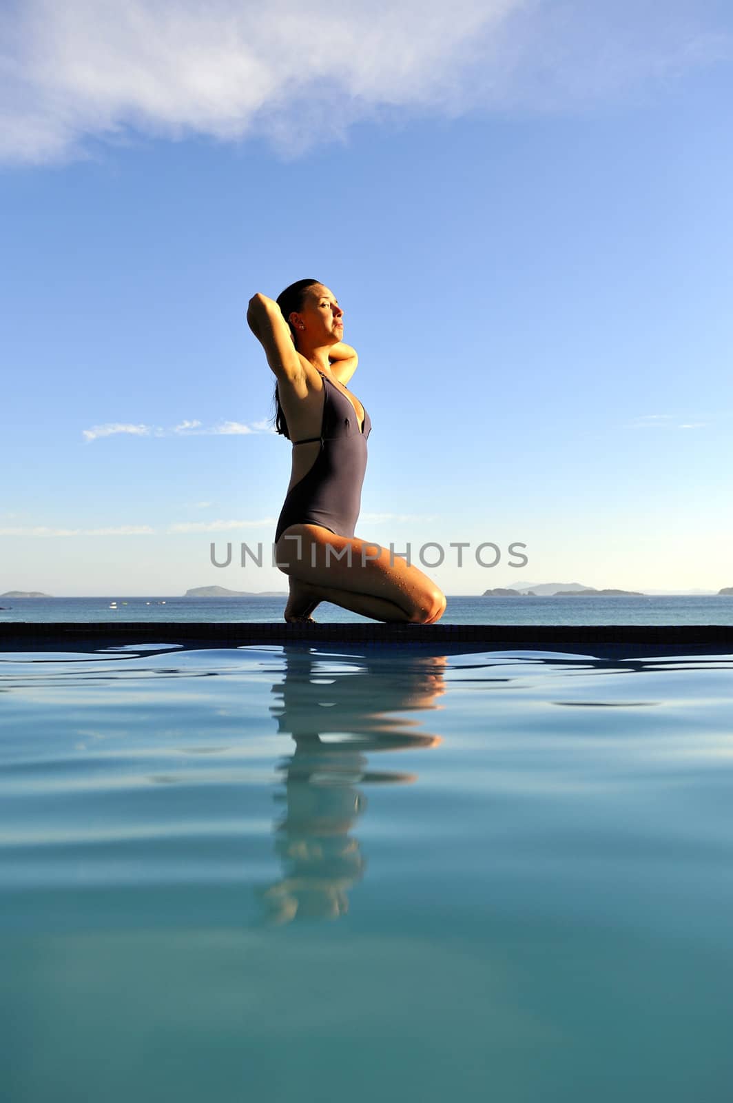 Woman relaxing on a swimming pool with a sea view 
