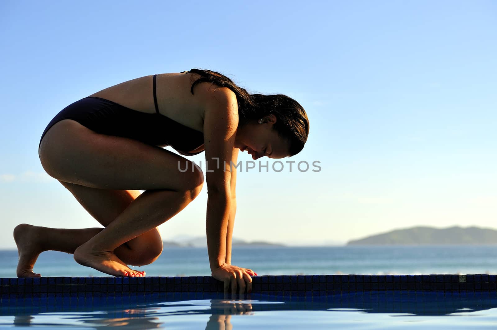 Woman relaxing on a swimming pool with a sea view 
