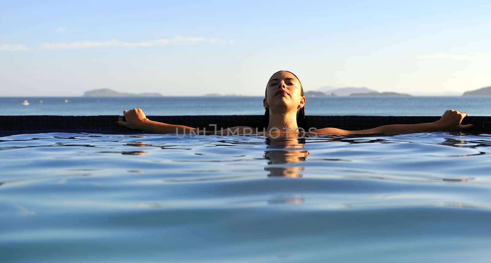 Woman relaxing on a swimming pool with a sea view 
