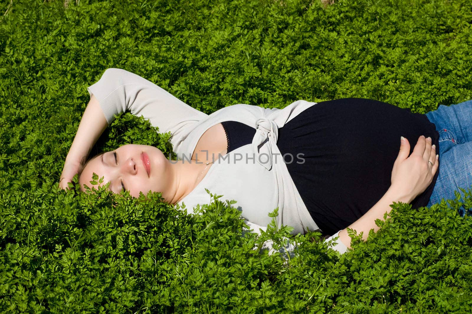 Calm pregnant woman enjoying lying in green grass