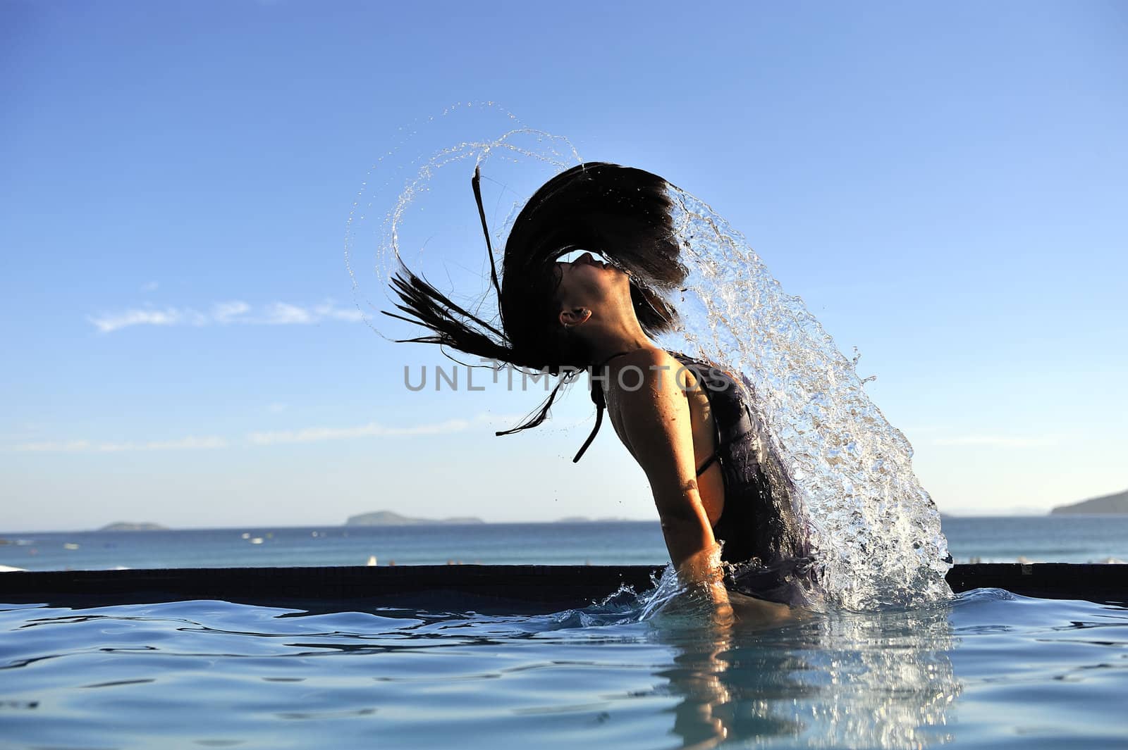 Woman relaxing on a swimming pool with a sea view 
