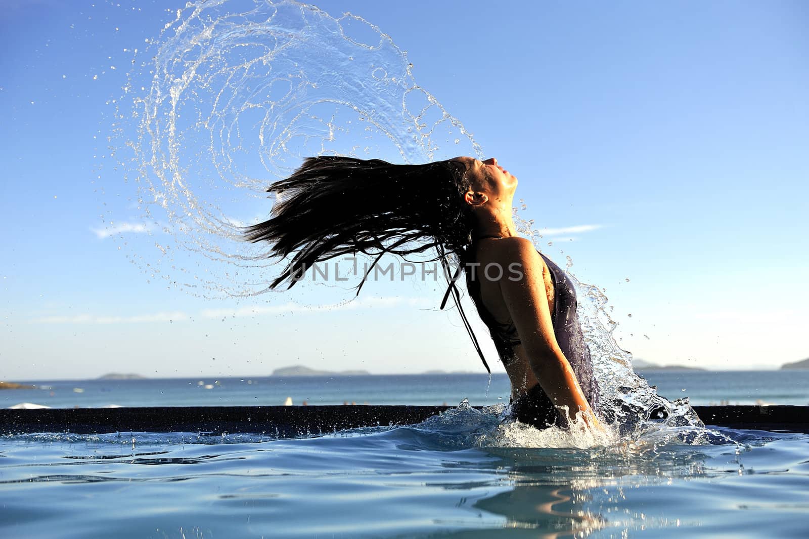 Woman relaxing on a swimming pool with a sea view 
