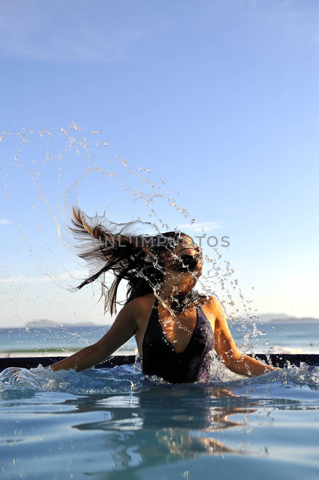 Woman relaxing on a swimming pool with a sea view 
