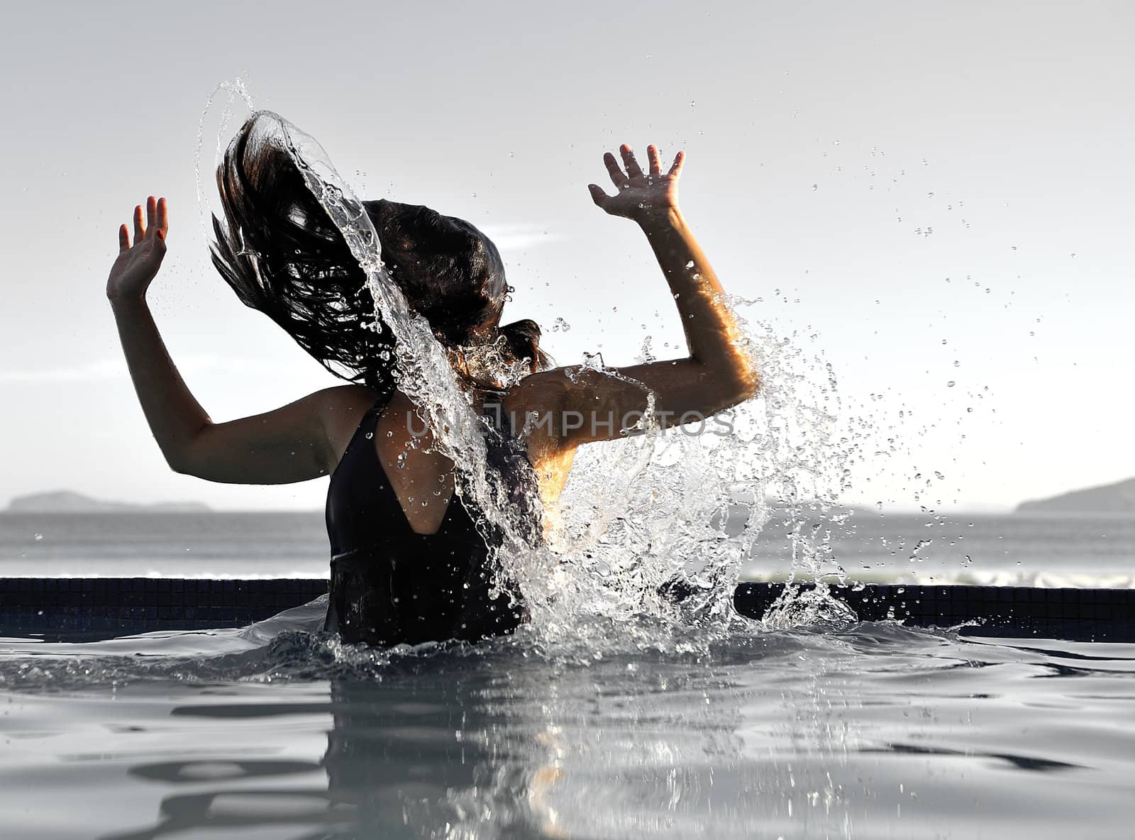 Woman relaxing on a swimming pool with a sea view 
