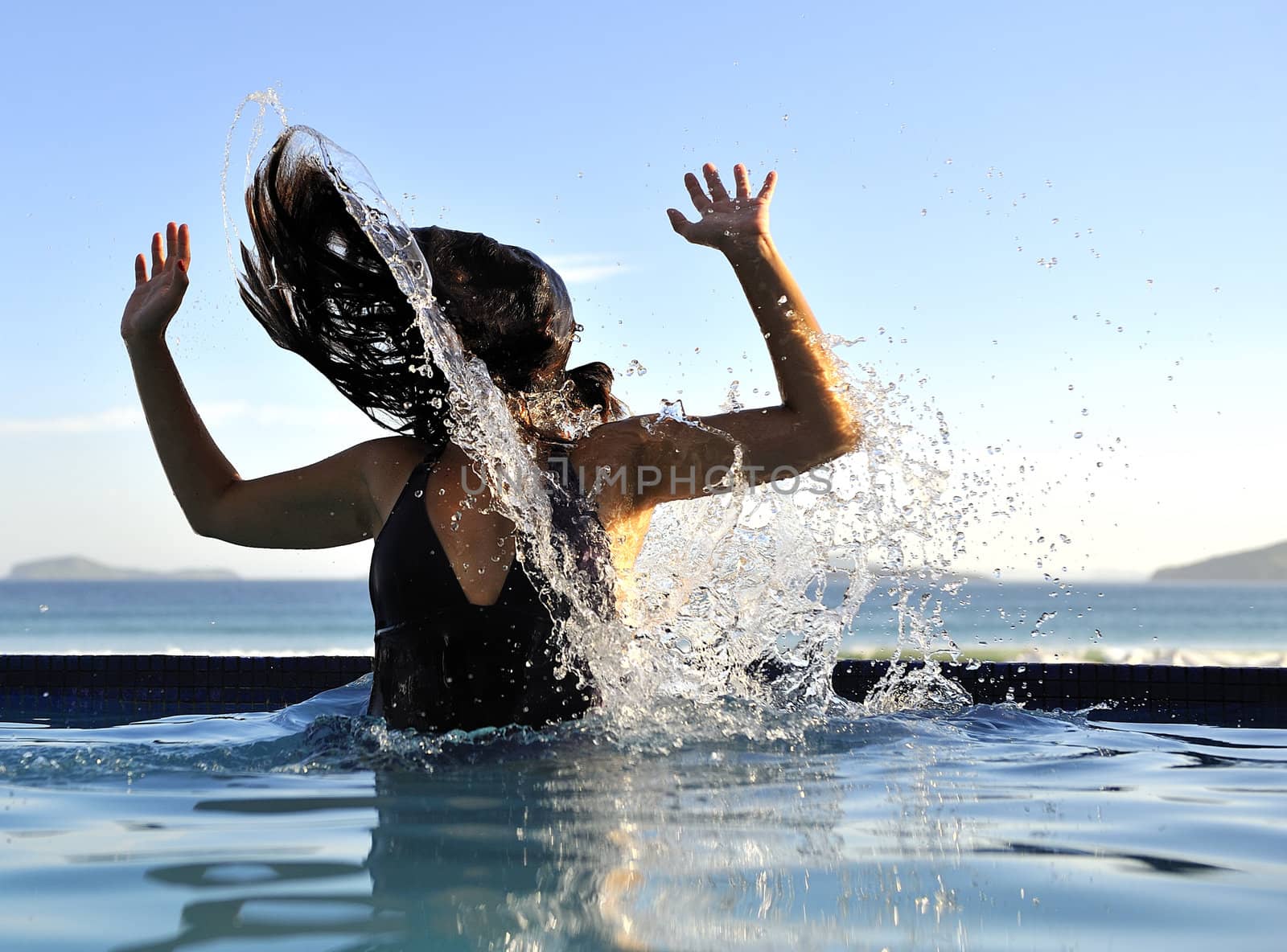 Woman relaxing on a swimming pool with a sea view 
