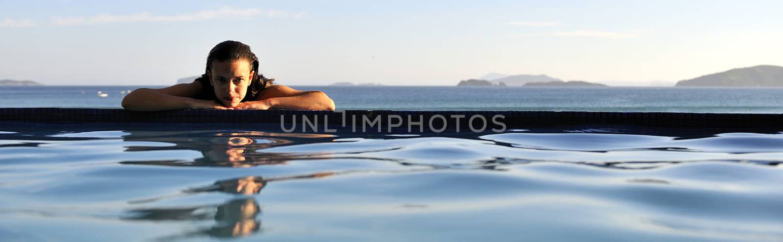 Woman relaxing on a swimming pool with a sea view 
