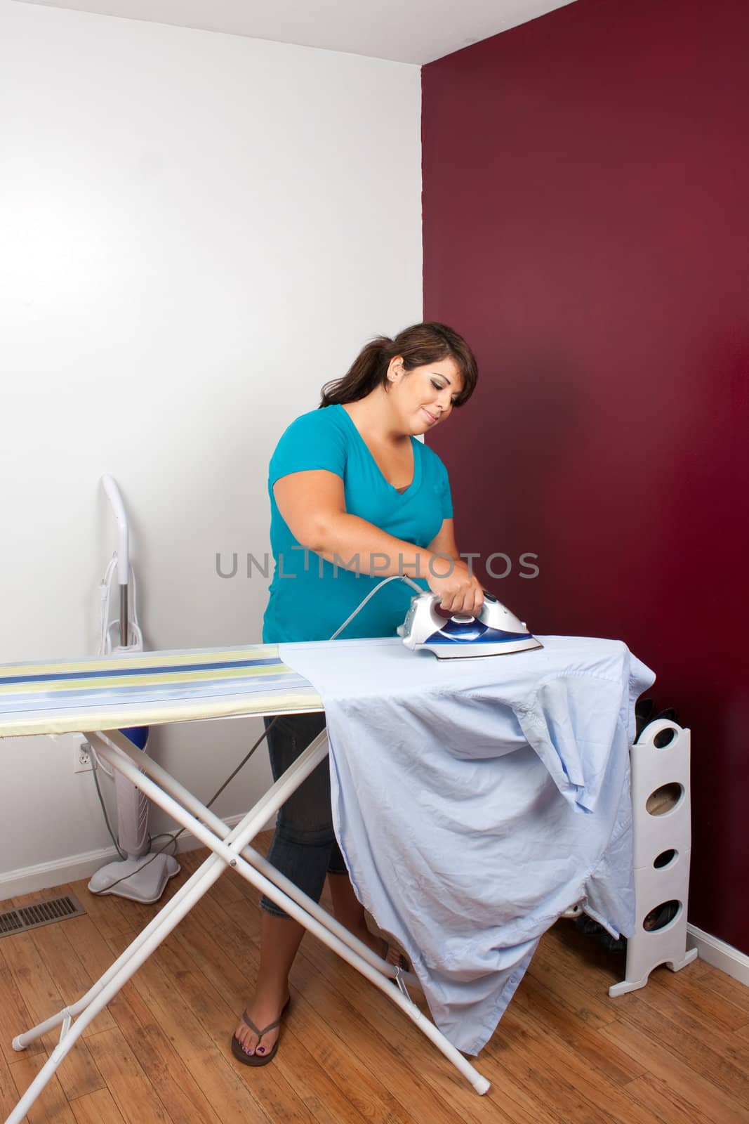 A young woman at home pressing some clothes on an ironing board.