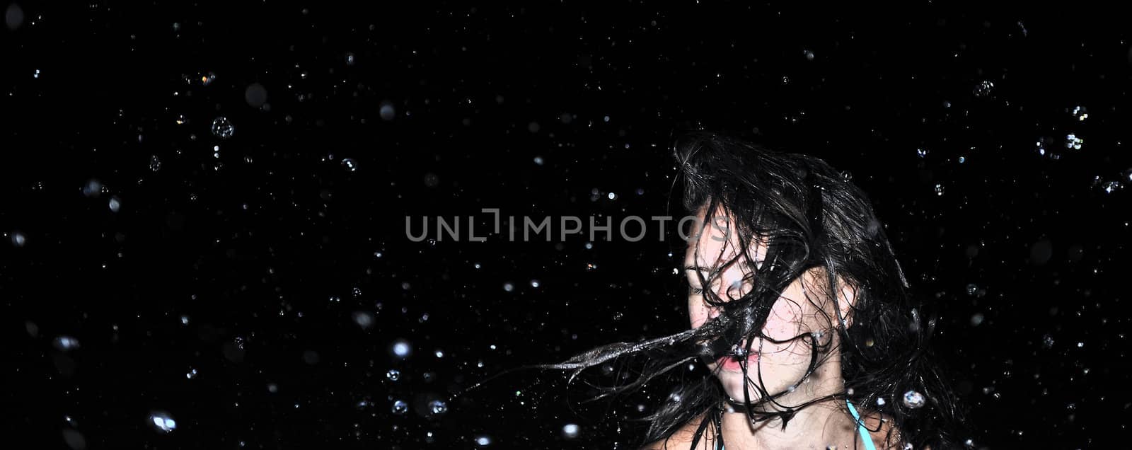 Beautiful swimsuit model splashing water on vacation
