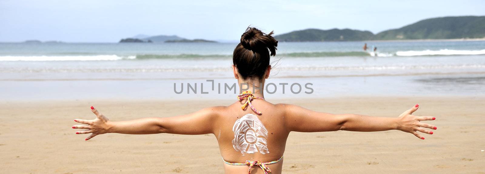 Woman taking sun with suncream draw on her back
