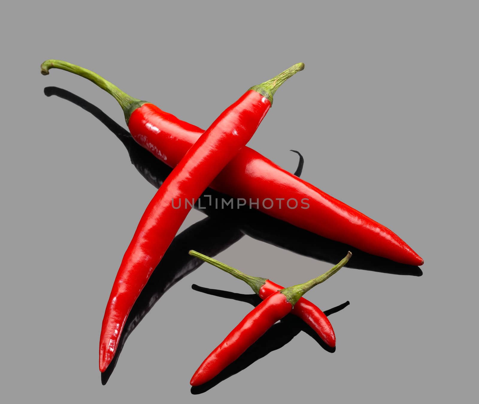 fresh red chili peppers over grey reflective surface