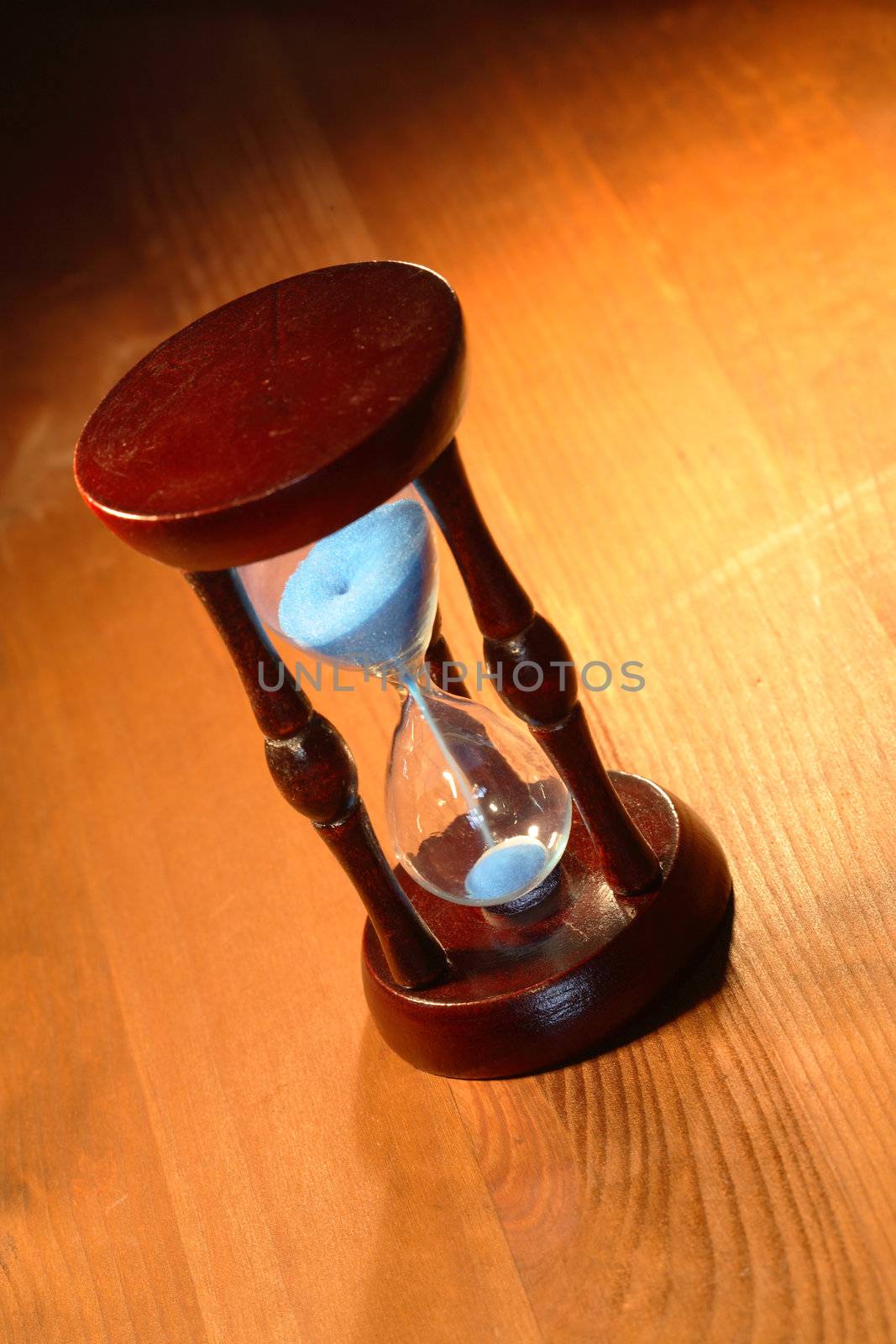 Vintage hourglass with blue sand standing on wooden background