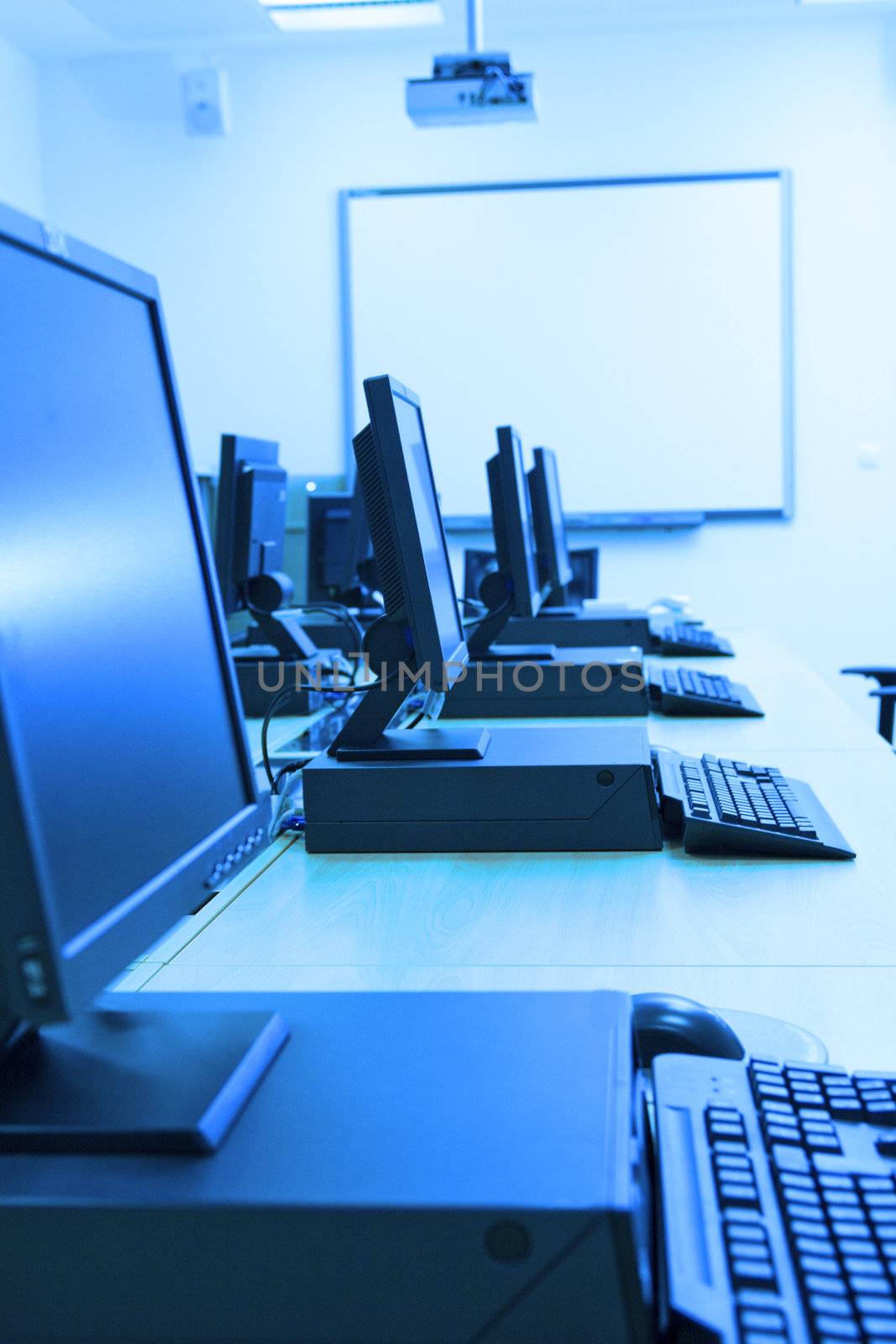 Room equipped with black computers. Image has blue tint.
