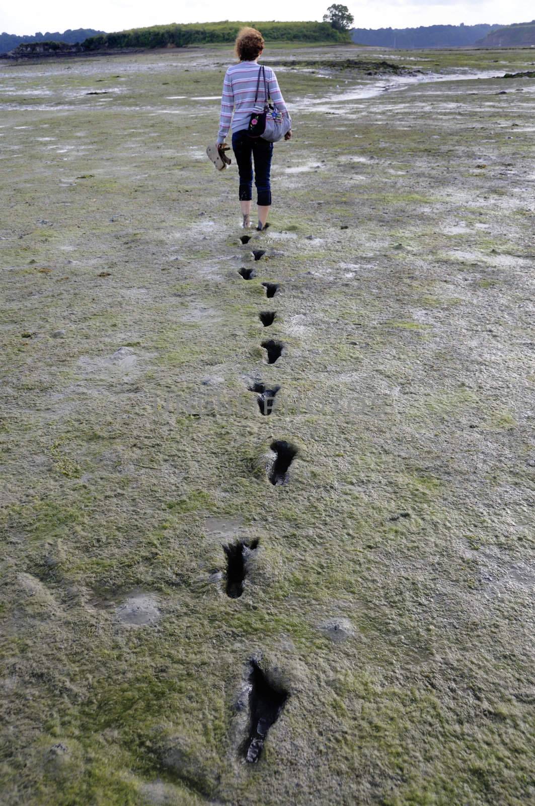 Girl walking barefoot trough mudflat in Brittany, France