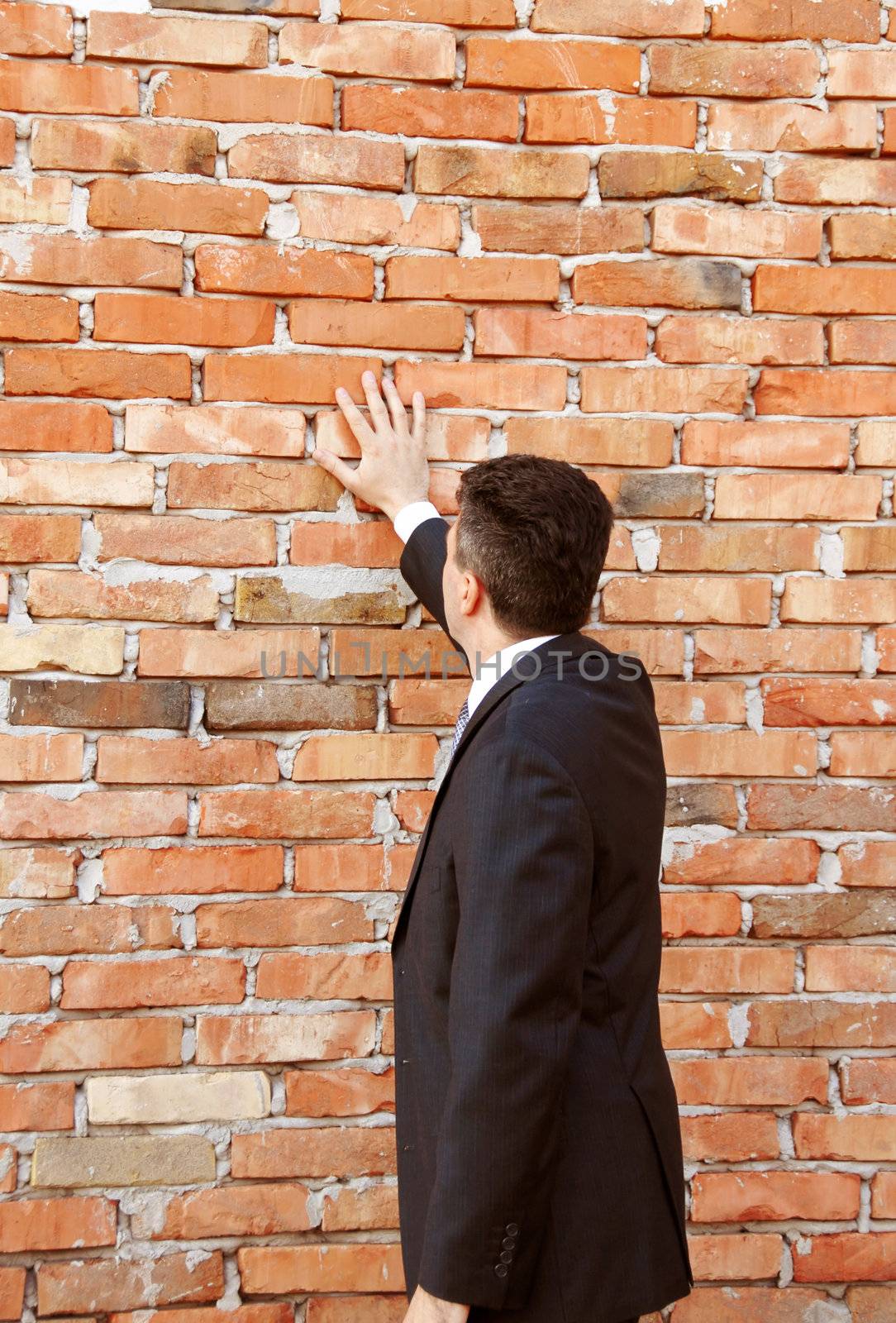 businessman hand in suit standing by brick wall