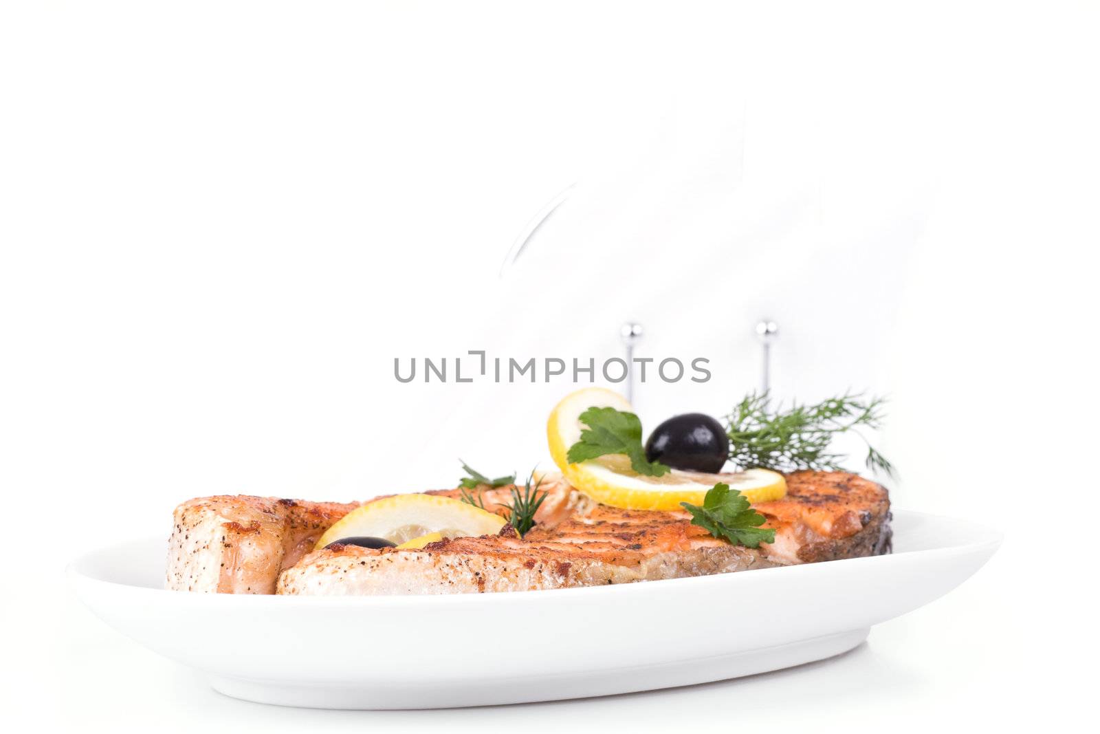 Appetizing Grilled Salmon with lemon, black olives and mixed greens isolated over white