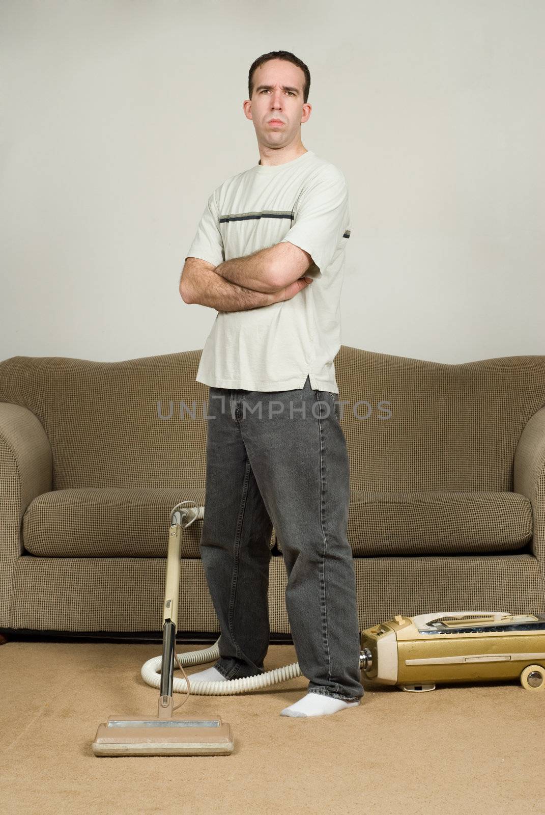 Full body view of a young man standing with his arms crossed, refusing to do anymore household chores