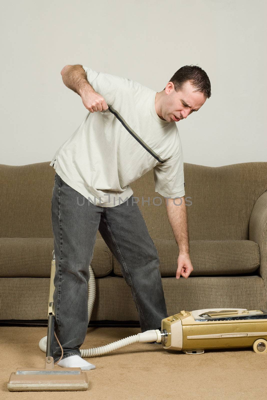 A mad man about to punch the vacuum cleaner because he is frustrated