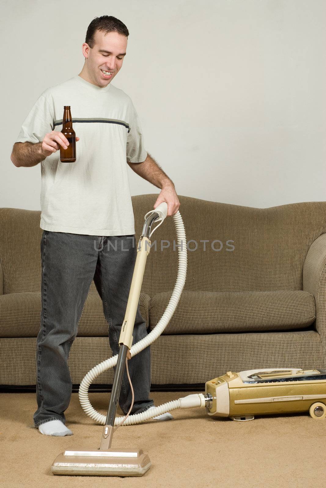 A young man drinking a beer while doing his household chores