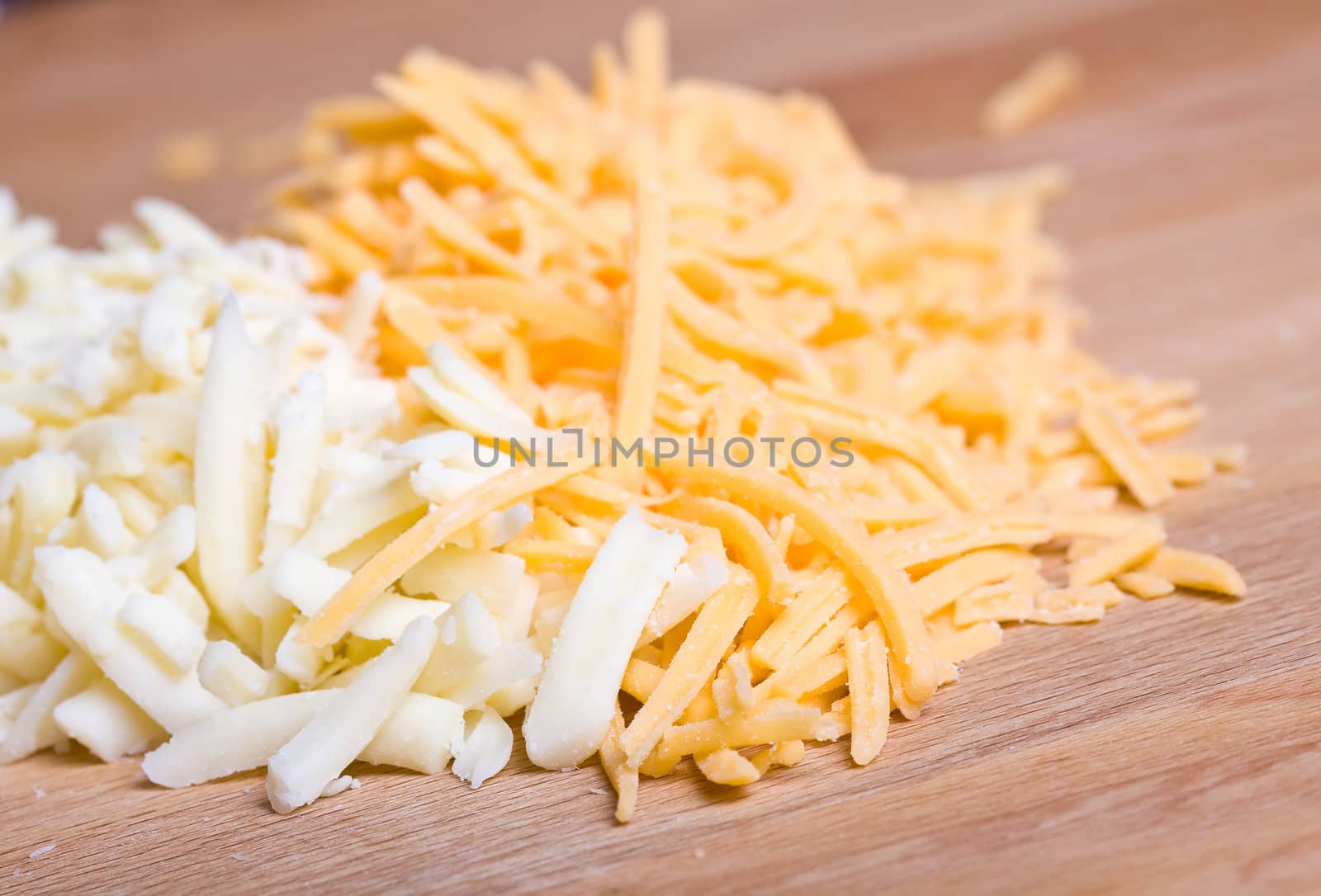 yellow and white cheddar cheese grated on a wood cutting board