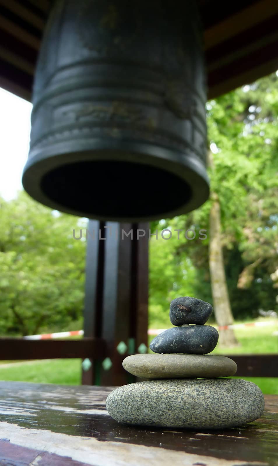 Zen stones on a peace of wood next to a japonese bell in a park