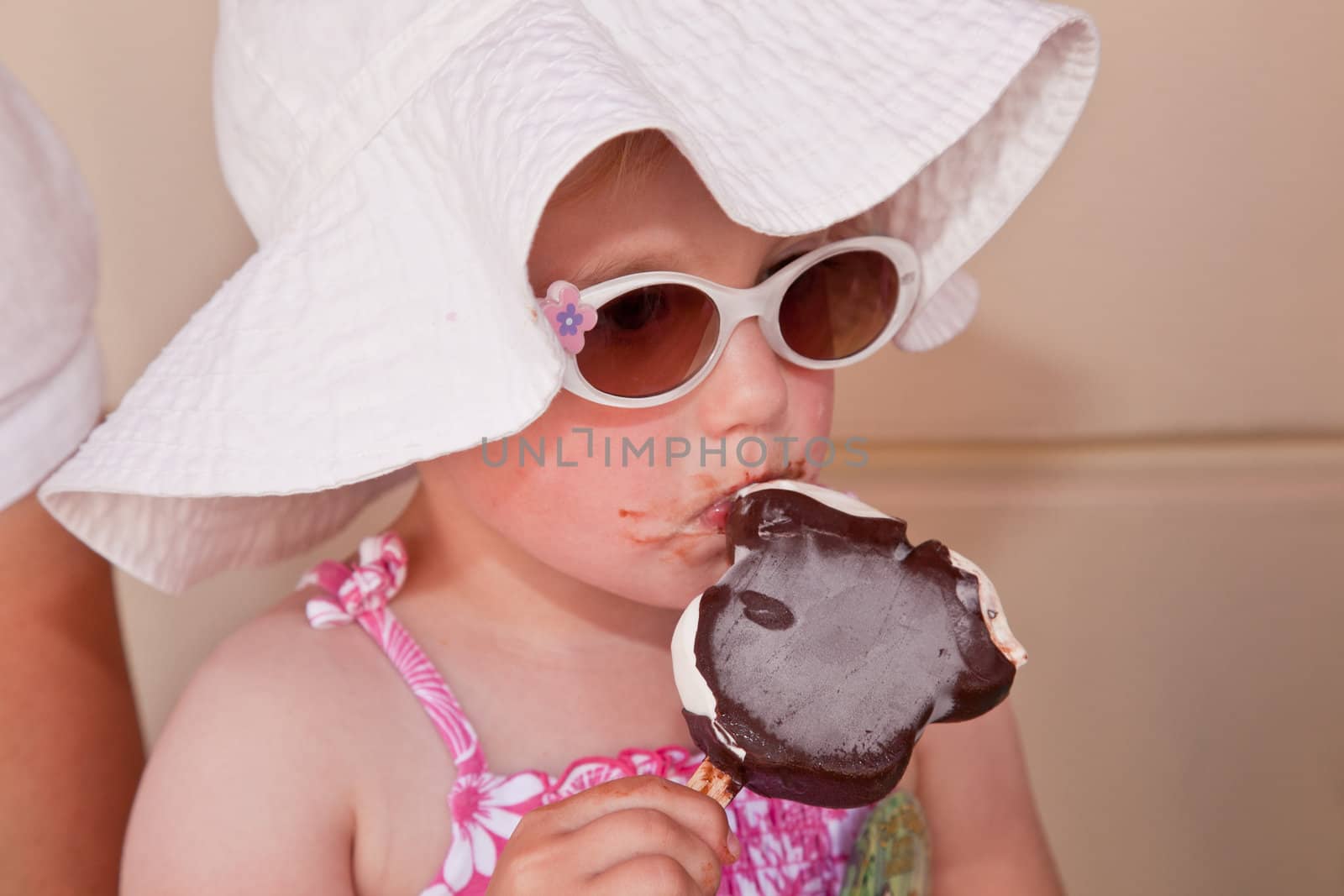 Cute little European toddler girl enjoying a piece of ice cream.