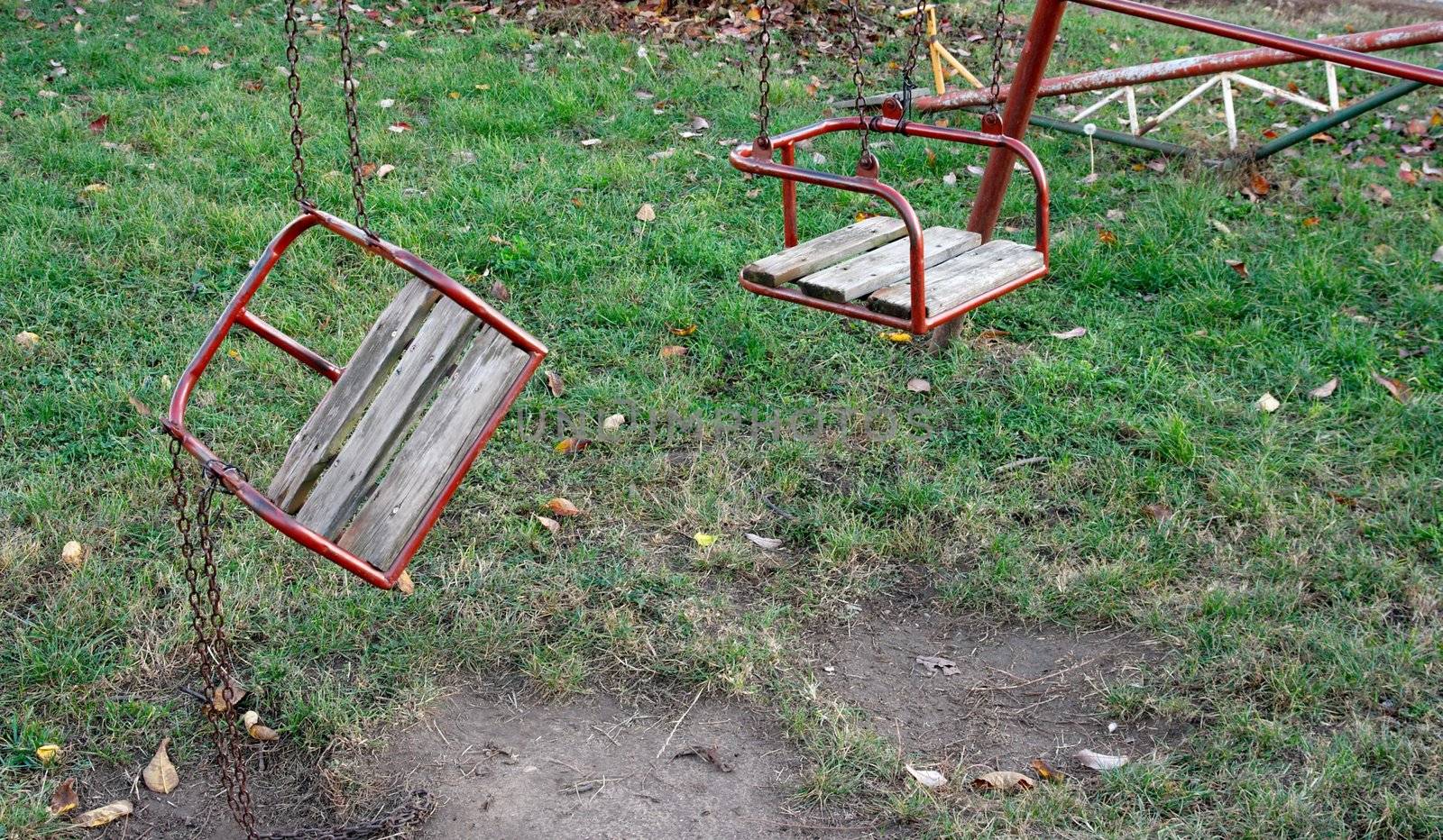 Two swings on a playground, one broken