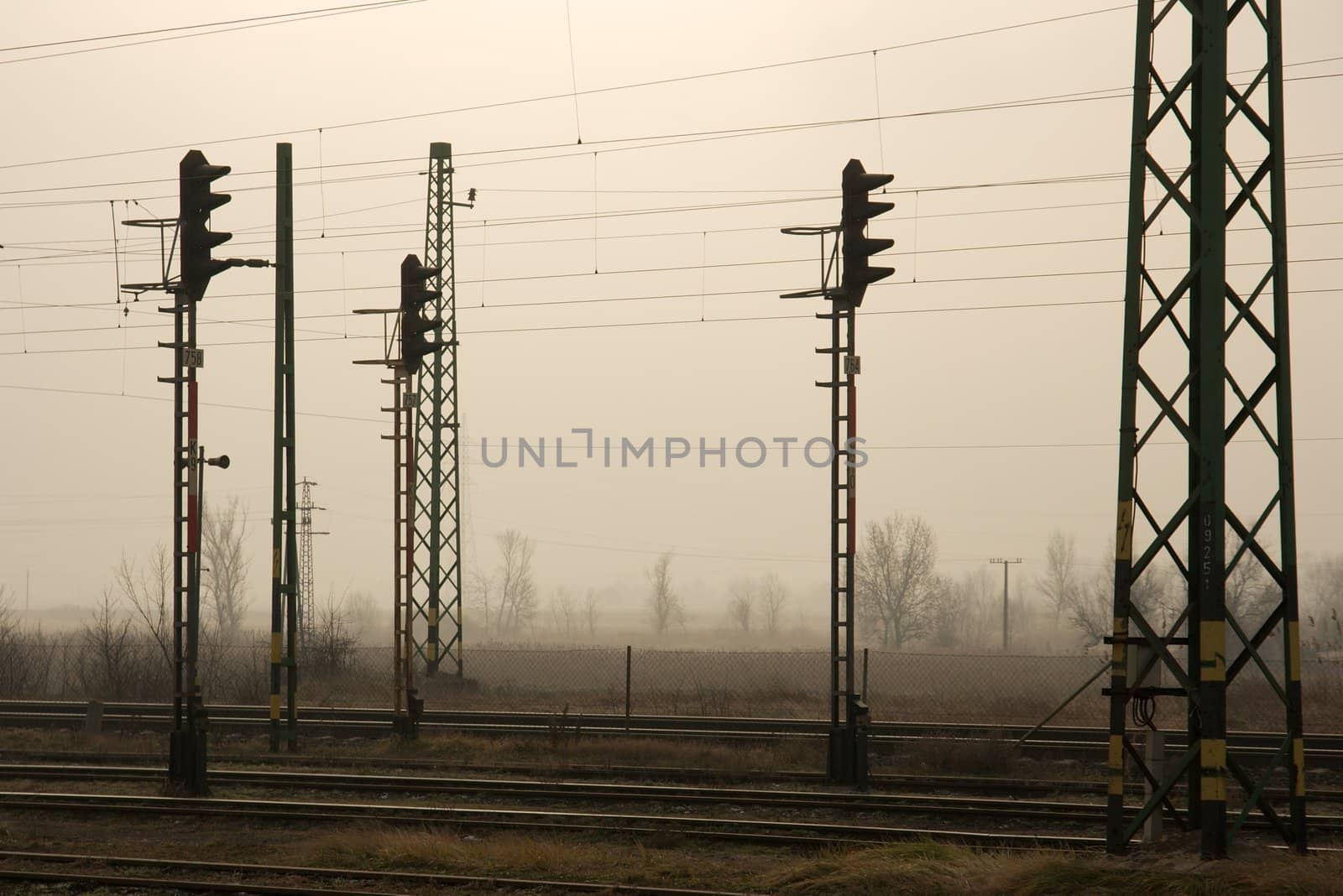 Railway tracks and traffic signals in a foggy landscape