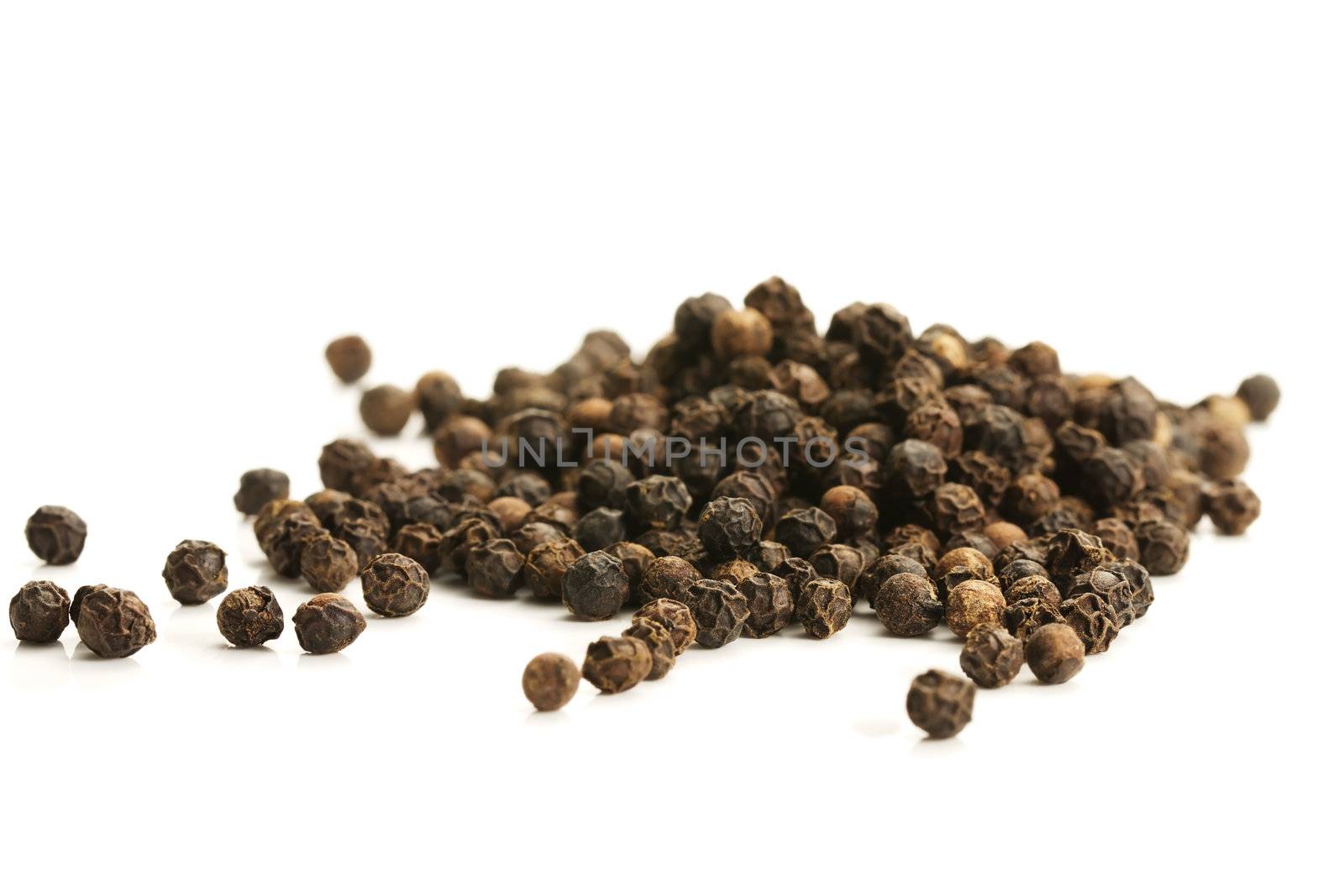 lot of black peppercorns on white background