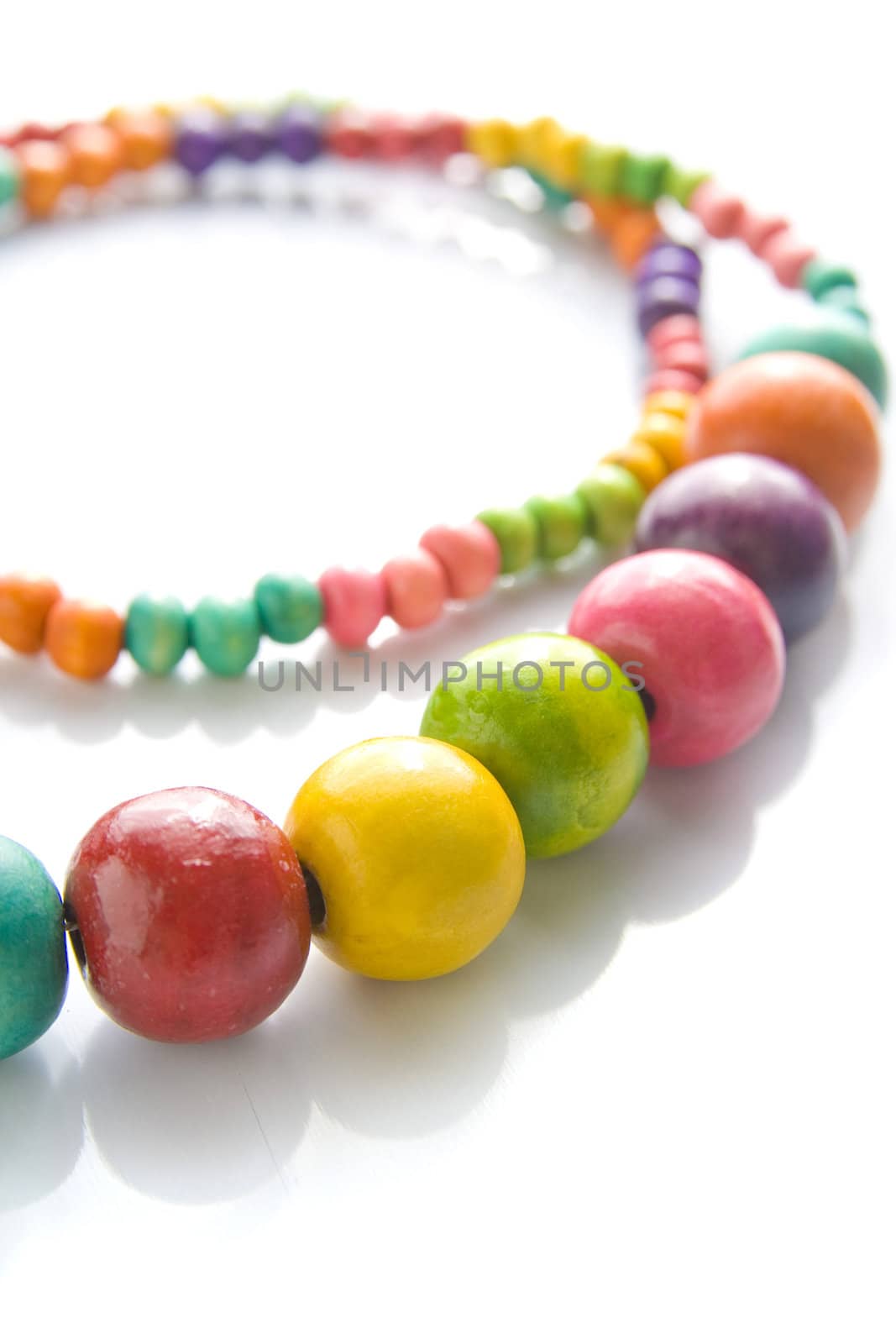 Colorful wooden necklace with vibrant colors and reflection.