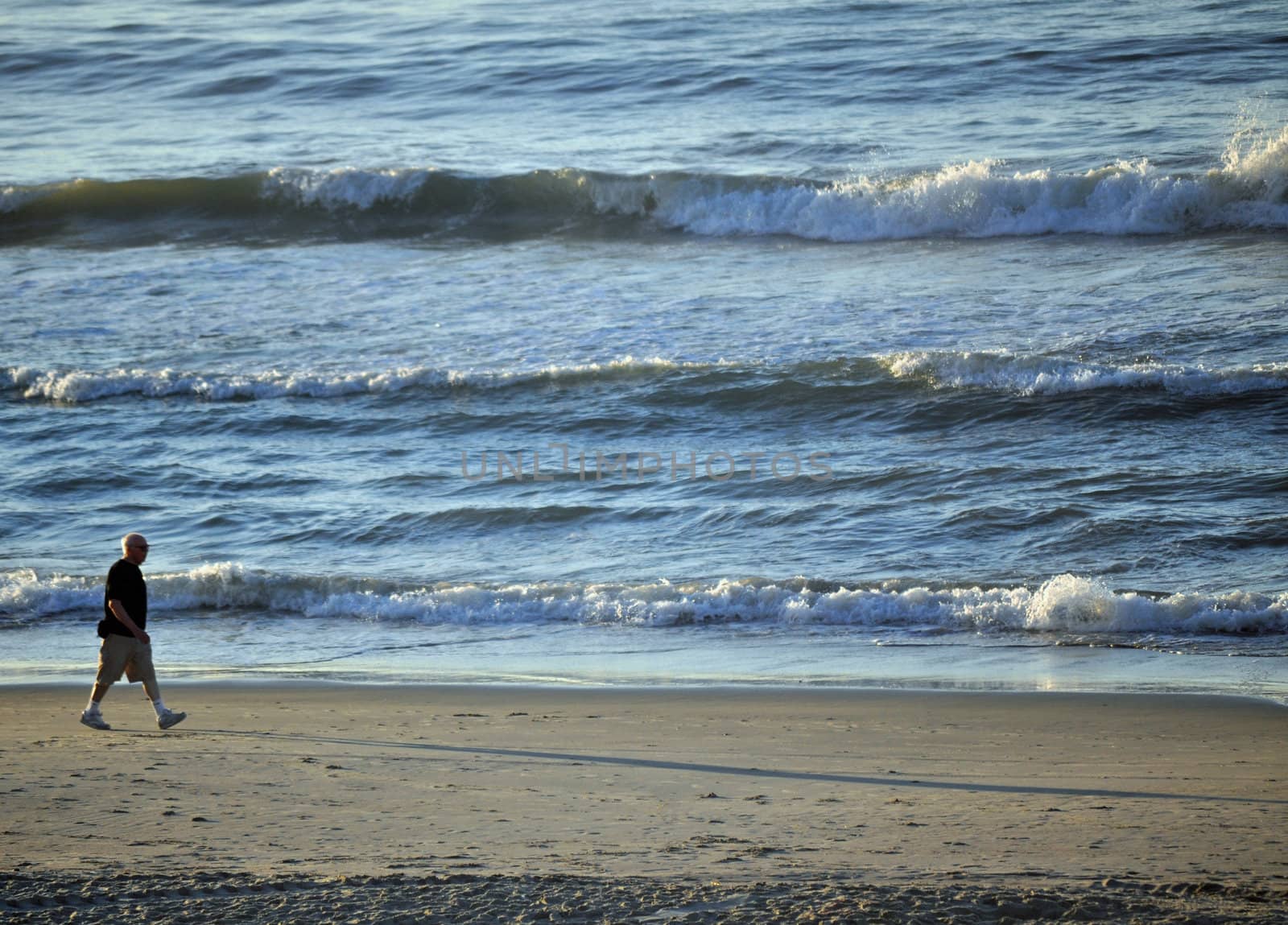 Man walking on beach by RefocusPhoto