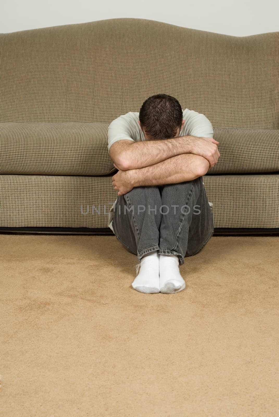 A depressed man hiding his face while sitting on the floor