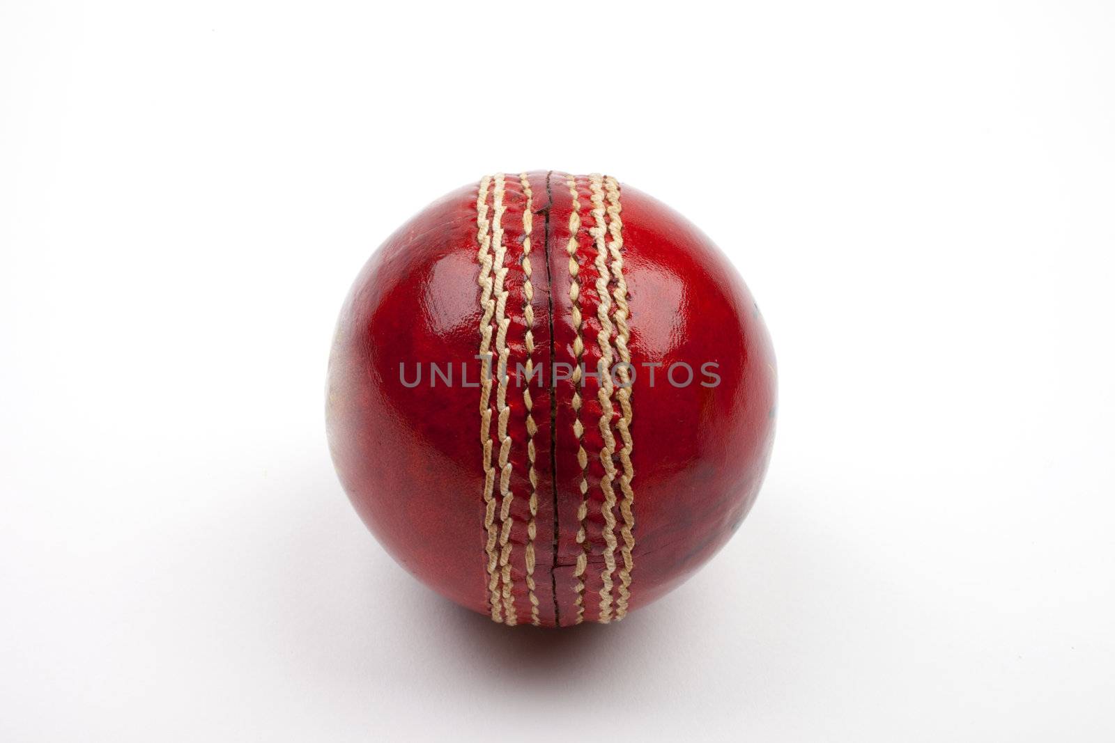 A Close-up shot of a red Cricket ball on white background.