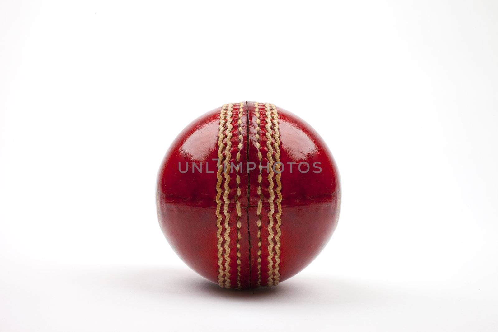 A Close-up shot of a red Cricket ball on white background.