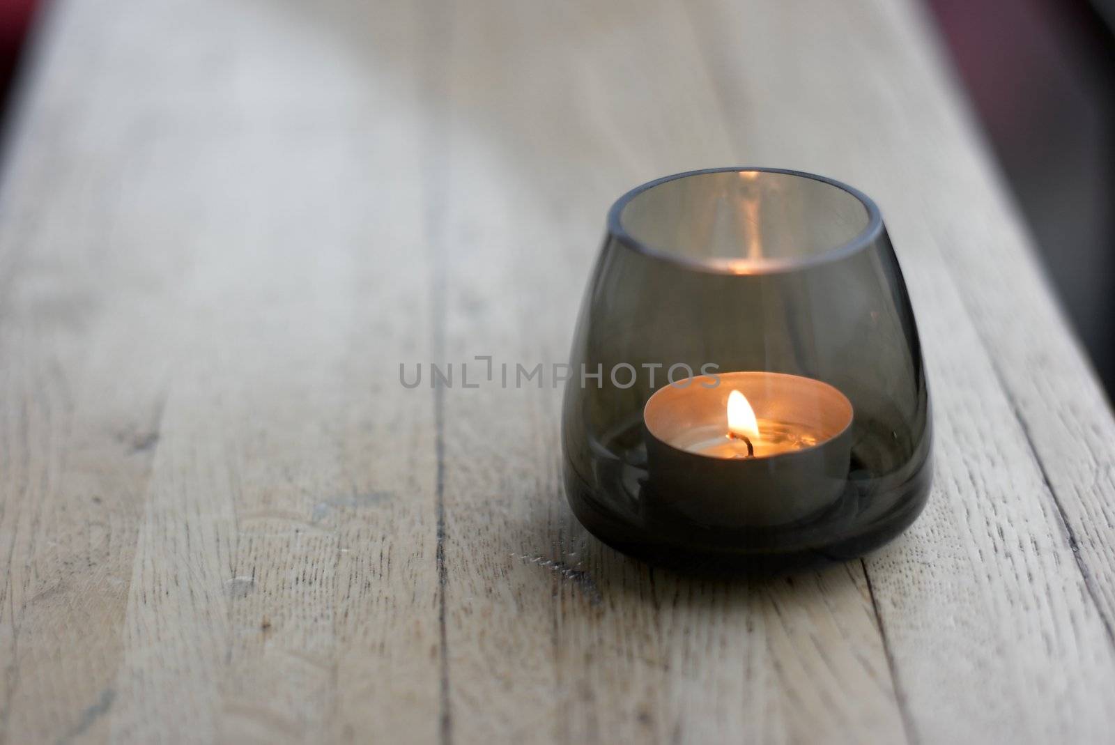 Small burning candle in a glass holder