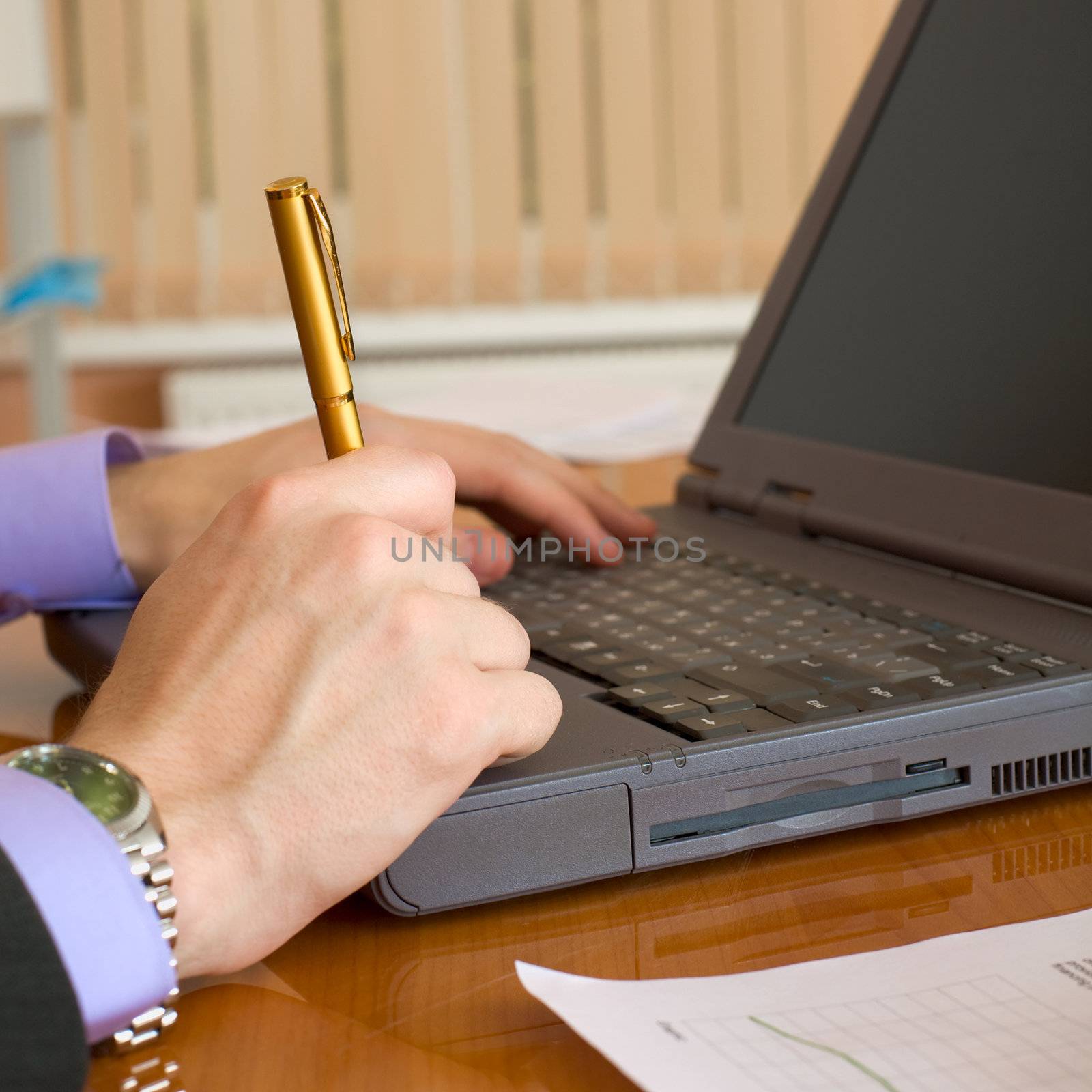 The laptop and man's hands with a pen
