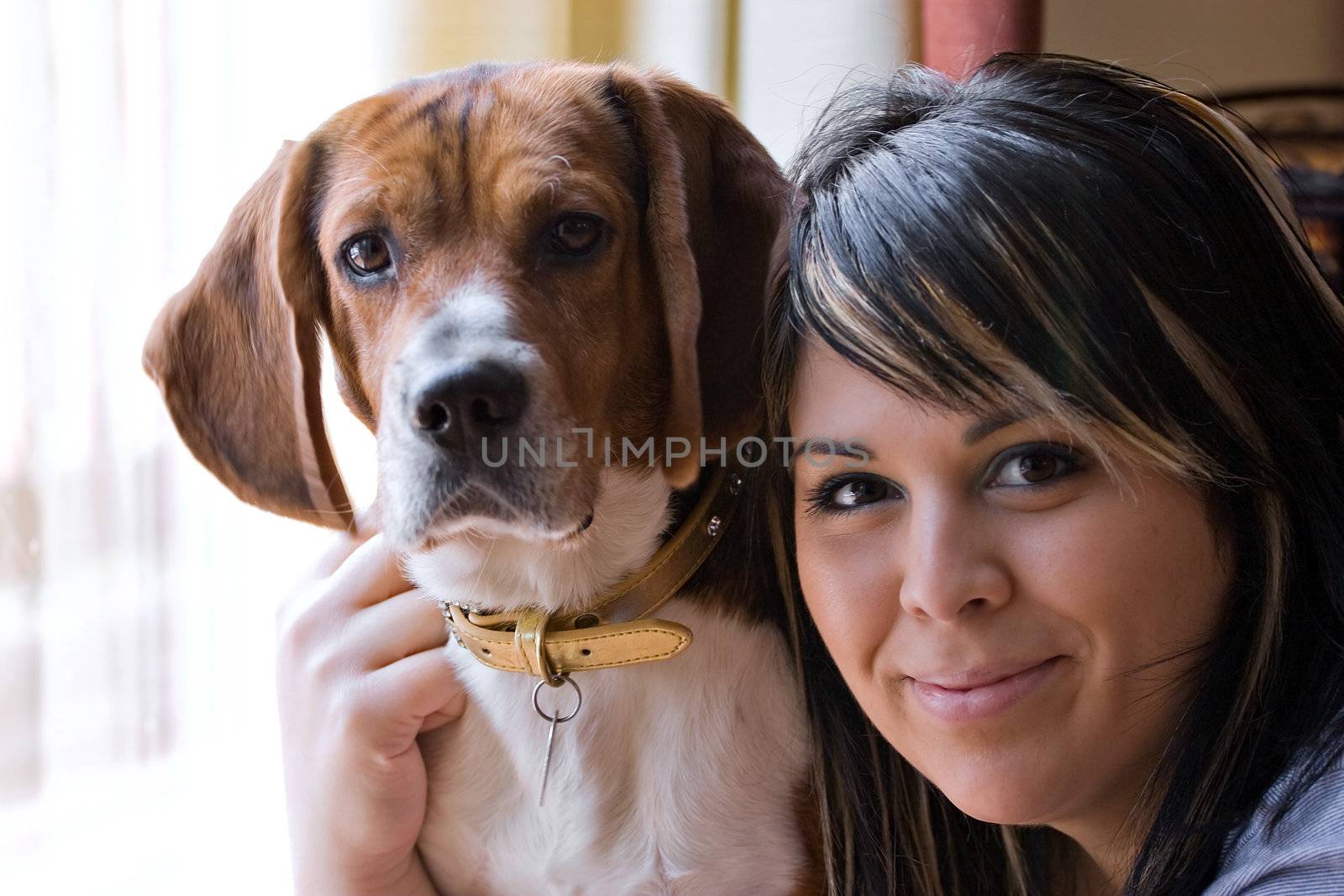 A pretty young woman posing with her beagle pup. Shallow depth of field.