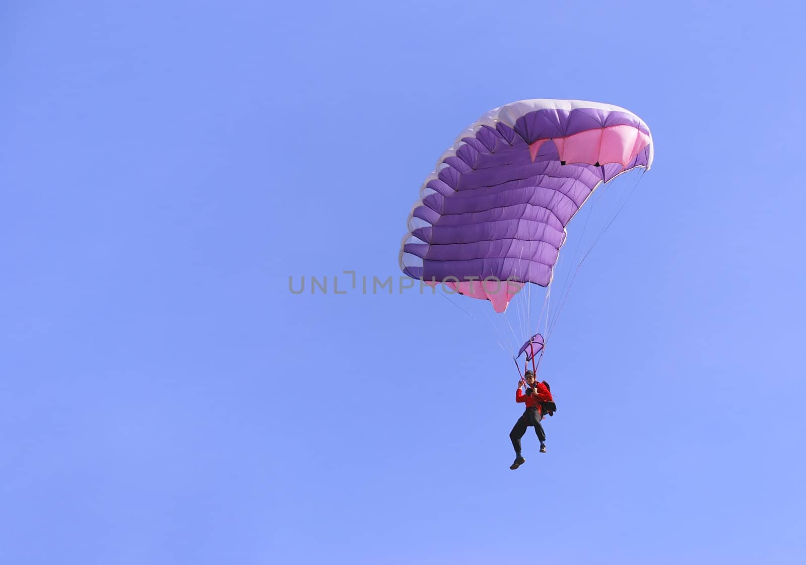 A purple parachute in a blue sky on a sunny day.