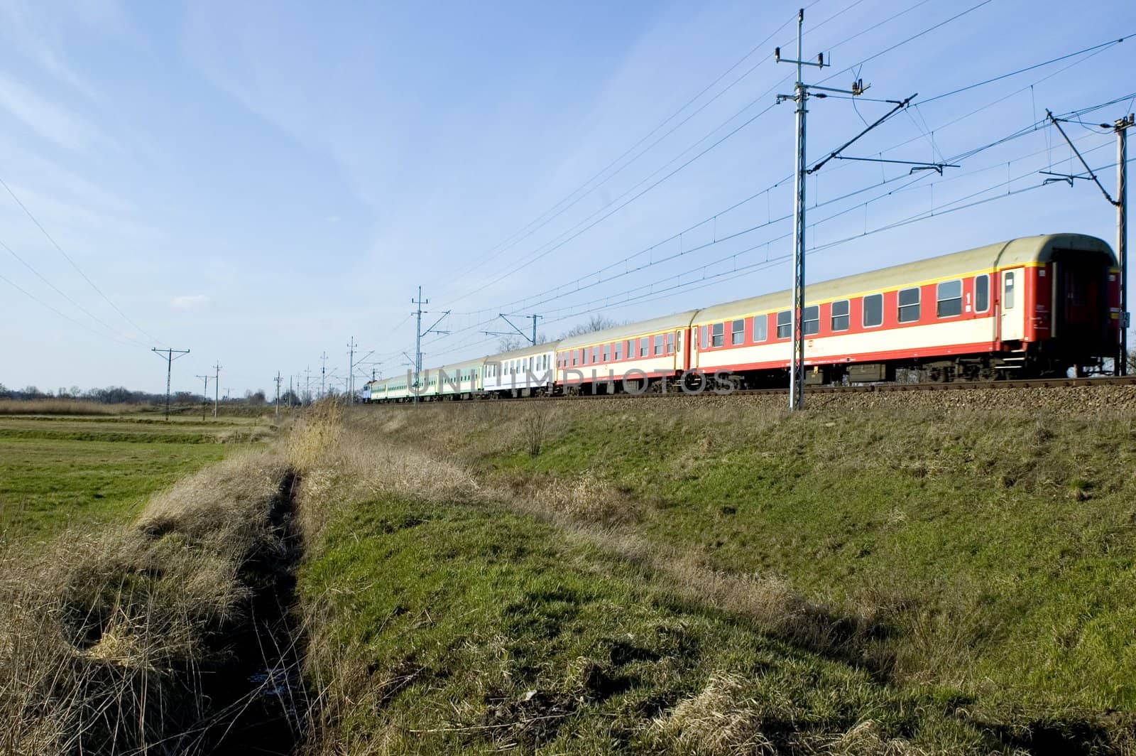 Train leaving Wroclaw city in Poland. Open field, green meadows at the beginning of spring.