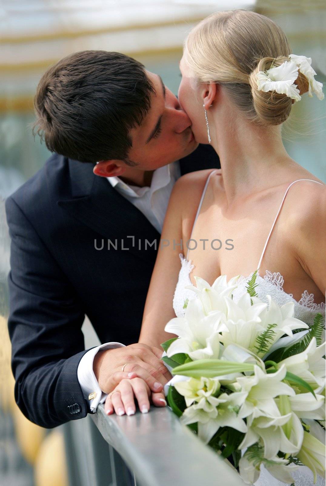 Half body portrait of attractive newlywed couple kissing.