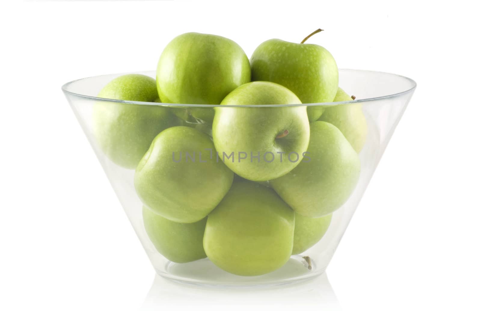 Glass bowl filled with green apples, isolated on white.