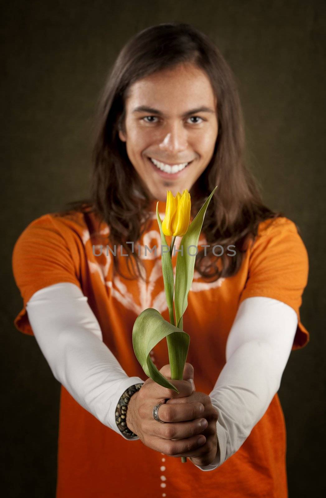 Handsome man reaching out with yellow tulip flower
