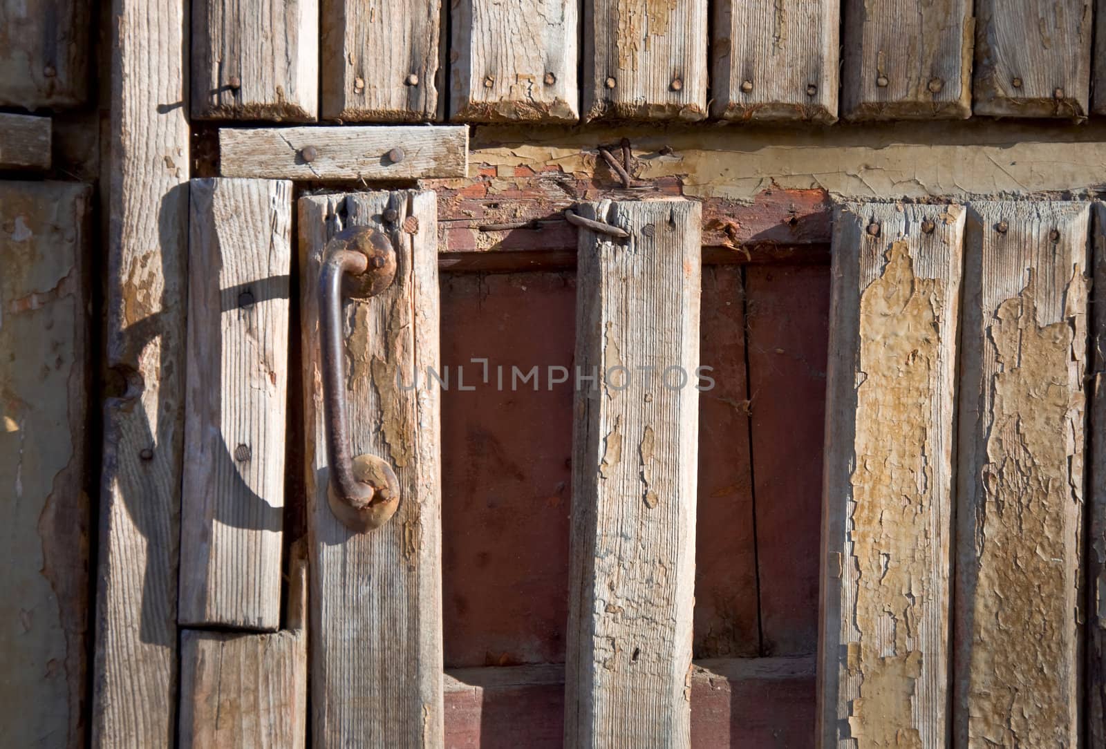 Fragment of an old wooden door with a handle. Close-up, front.